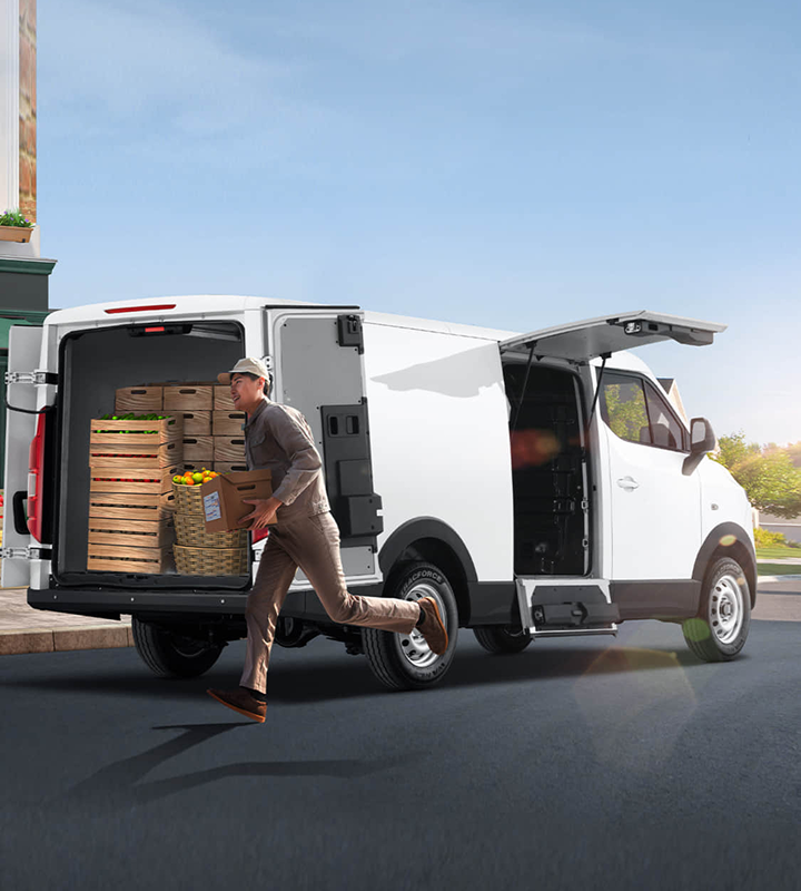 Repartidor transportando cajas de frutas y verduras desde una furgoneta blanca KARRY